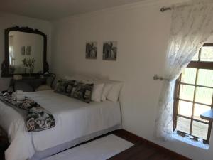 a bedroom with a white bed and a mirror at Kromrivier Farm Stays and Addo B & B in Paterson