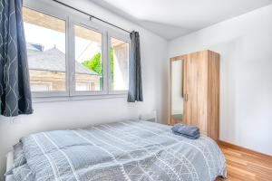 a bedroom with a bed and two windows at charmant T2 au bord de l'eau in Rochefort-sur-Loire