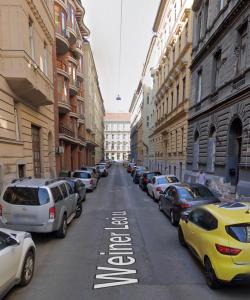 una calle de la ciudad con coches estacionados al costado de la carretera en YA House en Budapest