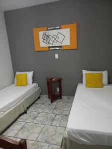 a room with two beds with yellow pillows and a table at Alliance Hotel in Bauru