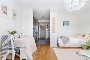Sala de estar blanca con mesa y cama en Warm, cosy place to live en Gotemburgo