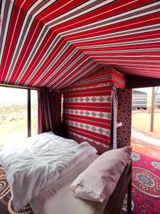 a bed in a room with a red and white canopy at Wadi Rum Trip in Wadi Rum