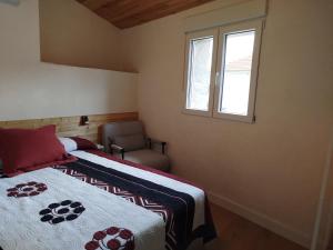 a bedroom with a bed and a chair and a window at Berrocal de Aldea en Cabo in Aldeaencabo de Escalona