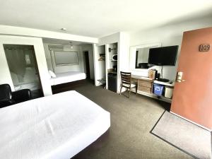 a hotel room with a bed and a flat screen tv at Arbutus Grove Motel in Parksville