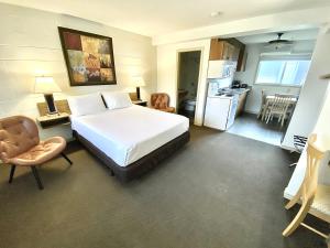 1 dormitorio con 1 cama blanca grande y cocina en Arbutus Grove Motel en Parksville
