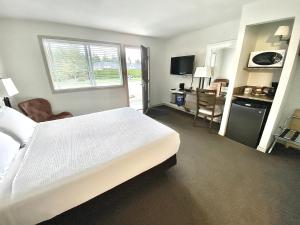 a hotel room with a large bed and a desk at Arbutus Grove Motel in Parksville