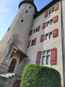 a building with red shuttered windows and a tower at Zimmer-B&B Restaurant Wirtshaus zur Trostburg in Teufenthal +3 photos