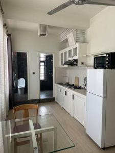 a kitchen with a table and a white refrigerator at Cozy 1BR in Downtown Phnom Penh BKK2 in Phnom Penh