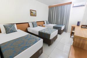 a hotel room with two beds and a desk at Hotel Dan Inn Ribeirão Preto in Ribeirão Preto