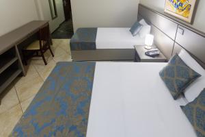 a hotel room with two beds and a desk at Hotel Dan Inn Ribeirão Preto in Ribeirão Preto