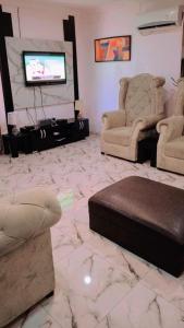 J Lounge في Ikorodu: غرفة معيشة مع كرسيين وتلفزيون بشاشة مسطحة