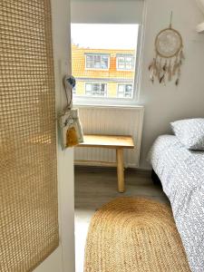 1 dormitorio con cama y mesa junto a una ventana en Vakantiehuis Egmond aan Zee met parkeerplaats, en Egmond aan Zee