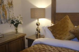 1 dormitorio con 1 cama con lámpara y un jarrón de flores en The Barrington Guesthouse Hotel, en Scarborough
