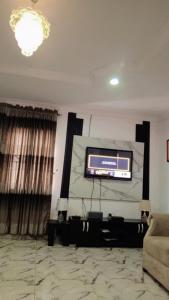 J Lounge في Ikorodu: غرفة معيشة مع تلفزيون بشاشة مسطحة وأريكة
