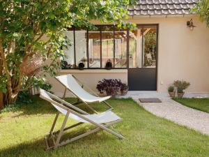 Deux chaises blanches assises dans l'herbe devant une maison dans l'établissement L'Atelier d'ici, à Thomery