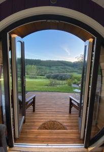an open door to a deck with a bench and a view at Luxury Glamping In North Yorkshire National Park & Coastal Area in Scarborough