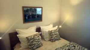 una camera da letto con cuscini bianchi e una foto appesa al muro di Face à la mer Corinne a Mers-les-Bains