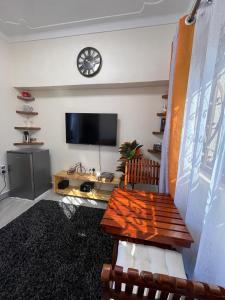 a living room with a table and a clock on the wall at Kindiha homes. in Seeta