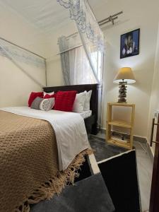 a bedroom with a large bed with red pillows at Kindiha homes. in Seeta