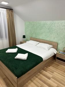 a bedroom with a large bed with two towels on it at Cabana Stânceni in Drăgoiasa