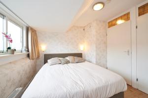 um quarto com uma cama com lençóis brancos e uma janela em B&B HutSpot em Amsterdã