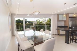 a dining room with a glass table and white chairs at Varandas do Atlântico 01B - Excelente apartamento em condomínio de luxo a beira mar - Piscina climatizada - Academia - (Consultar serviços de roupas de cama e banho) in Bombas