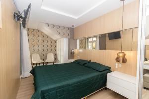 a bedroom with a green bed and two chairs at Varandas do Atlântico 01B - Excelente apartamento em condomínio de luxo a beira mar - Piscina climatizada - Academia - (Consultar serviços de roupas de cama e banho) in Bombas +46 photos