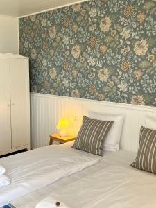 1 dormitorio con 1 cama y papel pintado con motivos florales en Sandkaas Badehotel, en Allinge