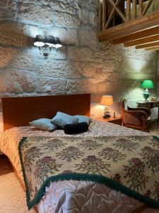 1 dormitorio con cama y pared de piedra en Casa Major, en Pegarinhos