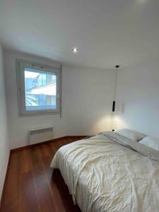 a white bedroom with a bed and a window at Gare - Elégant appartement pour pros ou touristes in Chambéry