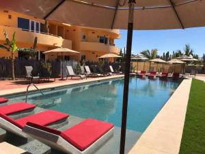 a swimming pool with lounge chairs and an umbrella at 1A Casa Un Amor, Cerritos Beach Condo in San Carlos