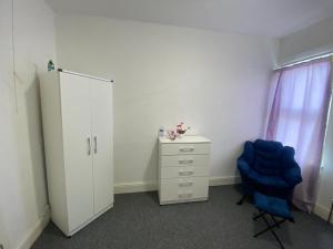 a bedroom with a blue chair and a dresser at Single Room in Erdington B23 in Birmingham