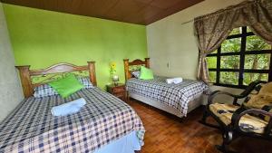 two beds in a room with green walls at Paraíso en Atitlán in Panaranjo
