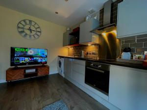 a kitchen with a tv and a clock on the wall at Town Hall View in Barnsley