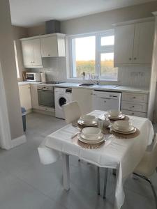 een witte keuken met een tafel met borden erop bij Hannahs Cottage 