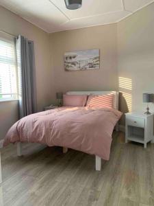 a bedroom with a bed with a pink comforter at Hannahs Cottage 