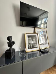 a dresser with pictures and a wine glass on it at Main Square Apartments Sylvi in Krakow
