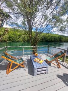 einen Picknicktisch und Stühle auf einer Terrasse neben dem Wasser in der Unterkunft Brvnara na obali reke Drine in Beserovina