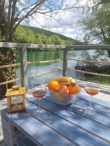 a table with a bowl of fruit and two glasses of wine at Brvnara na obali reke Drine in Beserovina