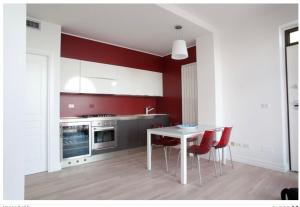 una cucina con pareti rosse, tavolo e sedie di Marino’s Apartment a Porto Recanati
