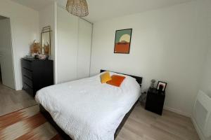 - une chambre avec un lit doté de draps blancs et d'oreillers orange dans l'établissement Beautiful appt with balcony in Blainville-sur-Orne, à Blainville-sur-Orne