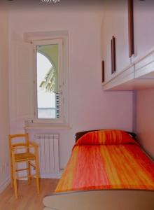Posto letto in camera con finestra e sedia di Marino’s Apartment a Porto Recanati