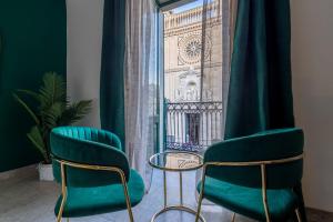 zwei Stühle und ein Tisch vor einem Fenster in der Unterkunft Baroque in Acireale