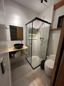 uma casa de banho com uma cabina de duche em vidro e um WC. em Cabana do Araujo em Paraty