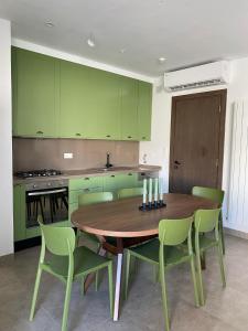 eine Küche mit grünen Schränken sowie einem Holztisch und Stühlen in der Unterkunft Villa Bali in Nabeul