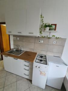 eine weiße Küche mit einer Spüle und einem Herd in der Unterkunft Apartments - Buffet 2B in Sveti Juraj