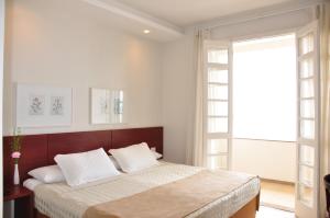 una camera bianca con un grande letto con cuscini bianchi di Hotel Rio Lancaster a Rio de Janeiro