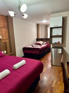 um quarto de hotel com duas camas e um frigorífico em Hotel Esmeralda em La Paz