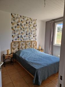 1 dormitorio con 1 cama con edredón azul y ventana en Gîte Pleine Nature, en Mas-des-Cours