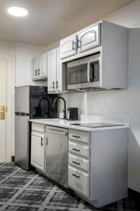 una cocina con armarios blancos y electrodomésticos de acero inoxidable en Hotel at Old Town, en Wichita